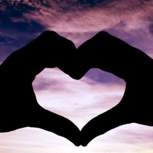 Manos en forma de corazón al atardecer