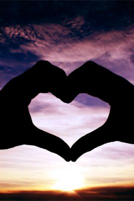 Manos en forma de corazón al atardecer